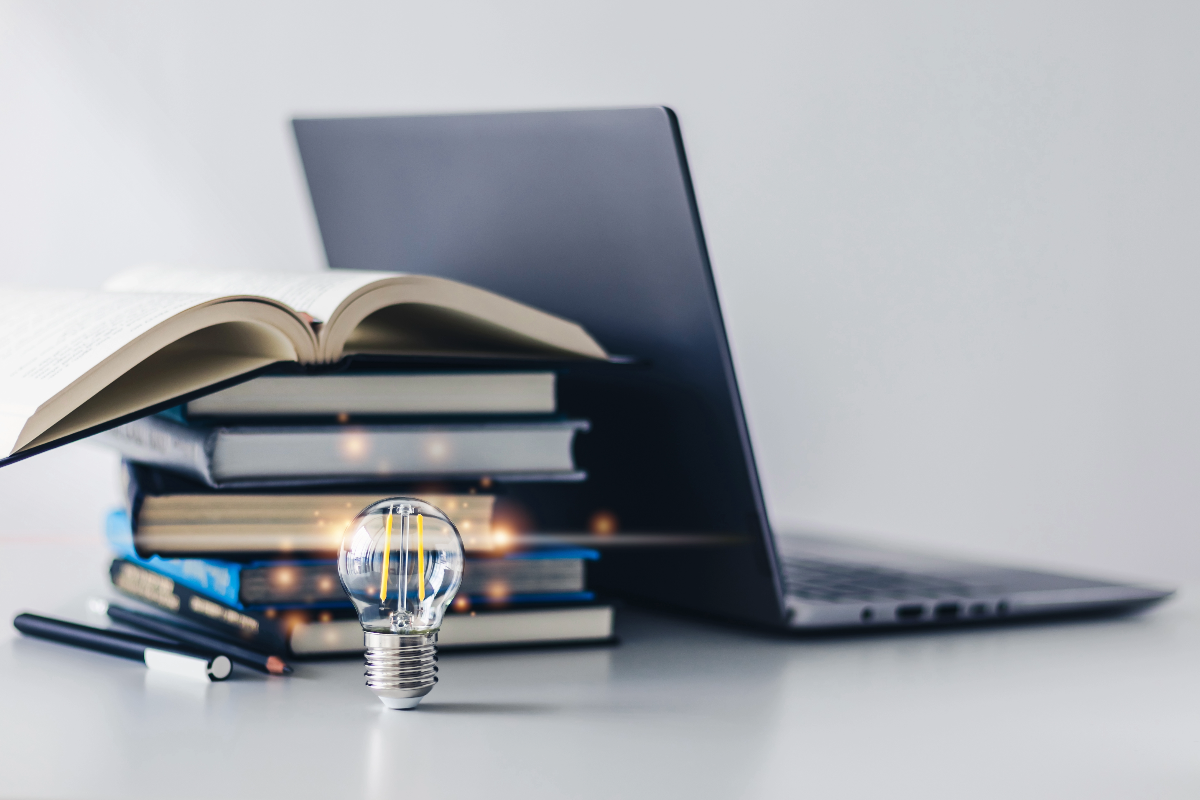 Laptop near books and a light bulb