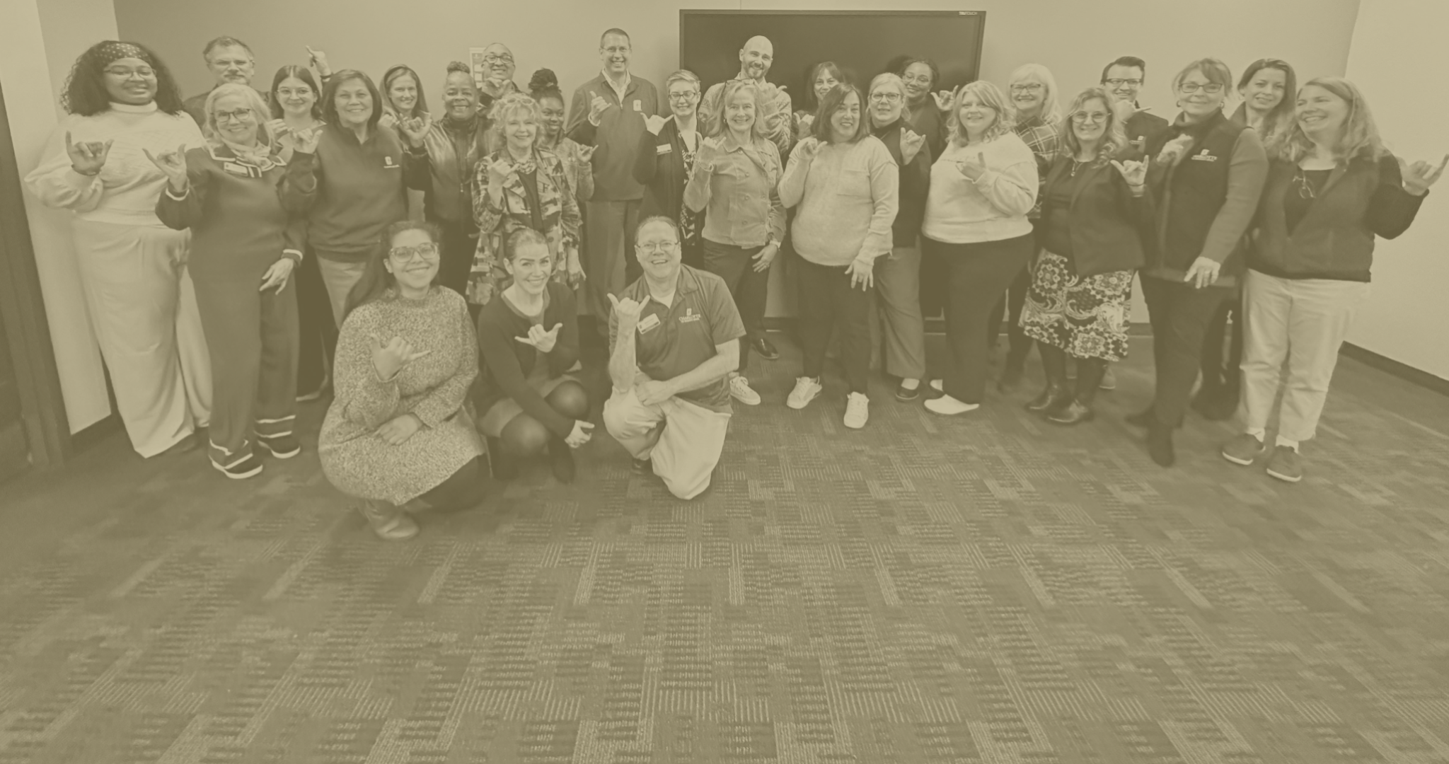 Graduate School staff team smiles while holding up Niner pickaxe with Dean Tolone in the center