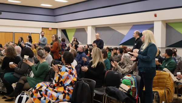 Crowd at Graduate Education Summit with several individuals clapping